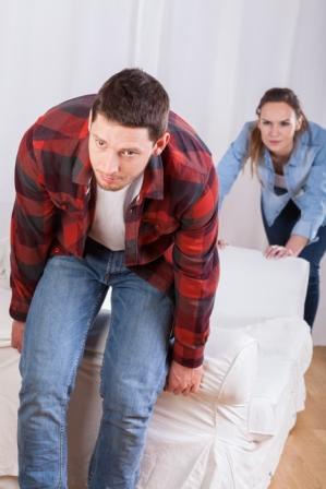 young couple moving the couch in new flat